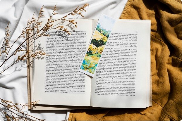 Livre ouvert posé sur un drap, avec un marque-page illustré